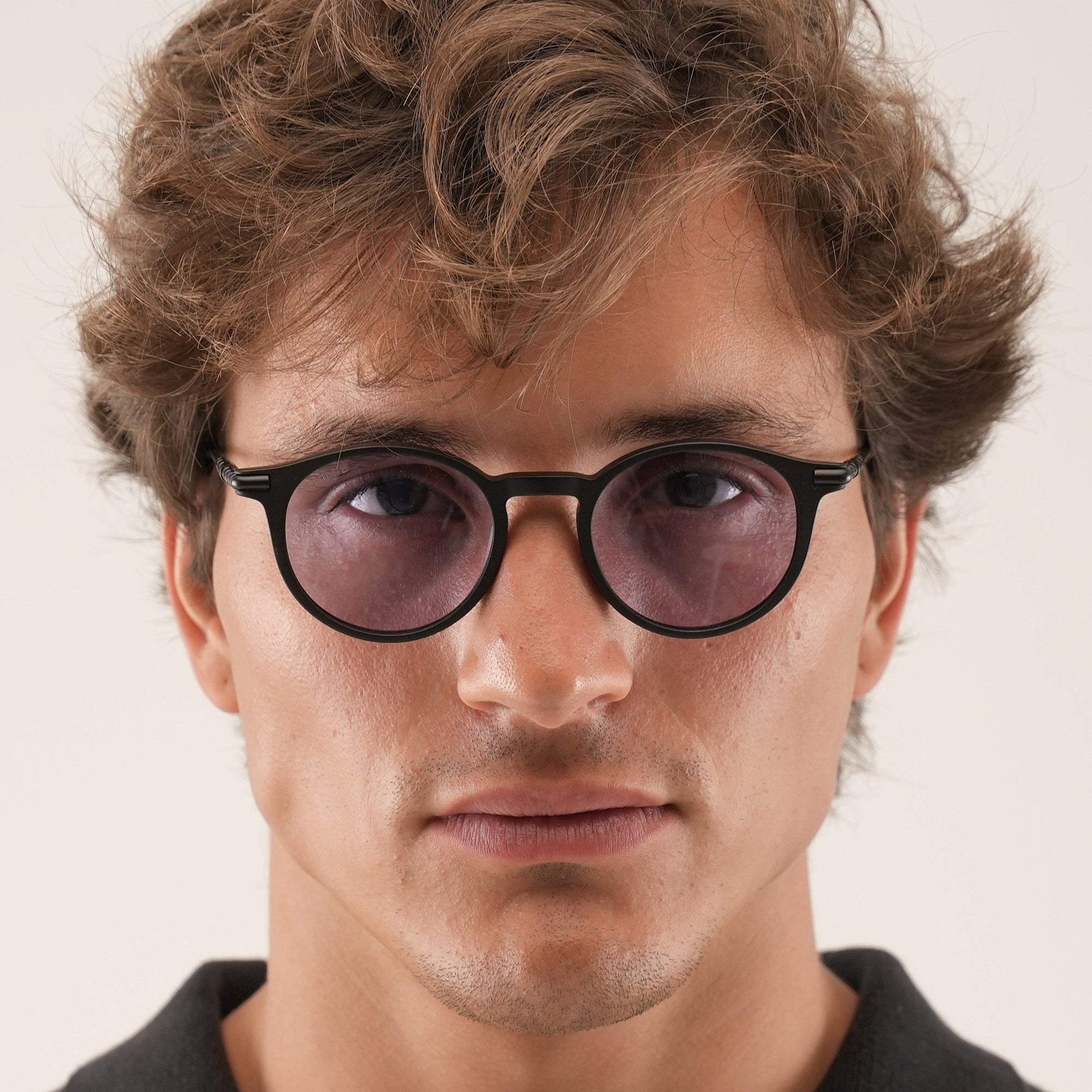 Man wearing black glasses with a neutral background