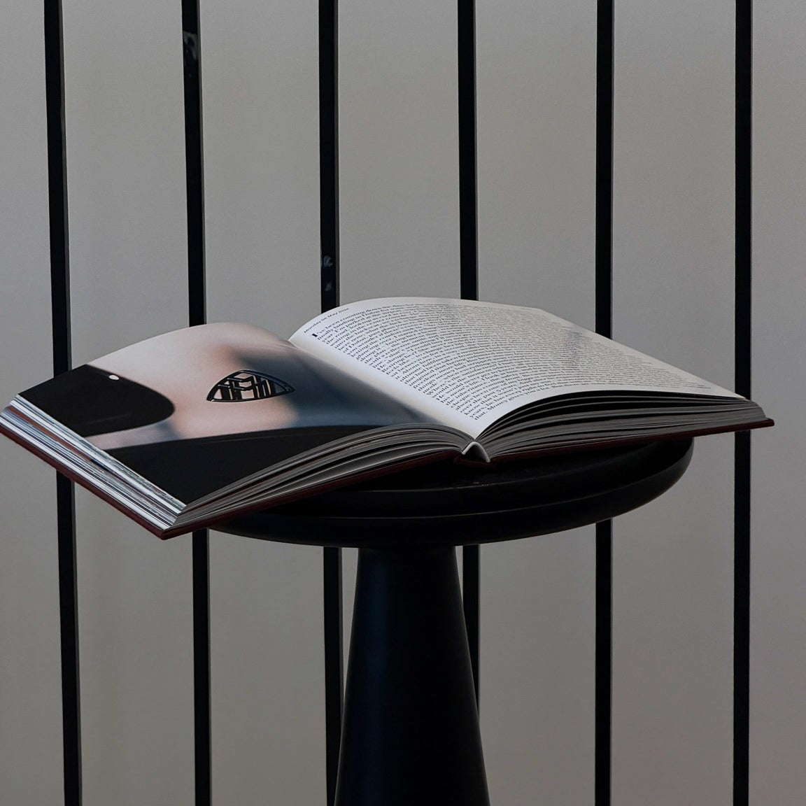 Open book on a small round table with a black metal railing in the background