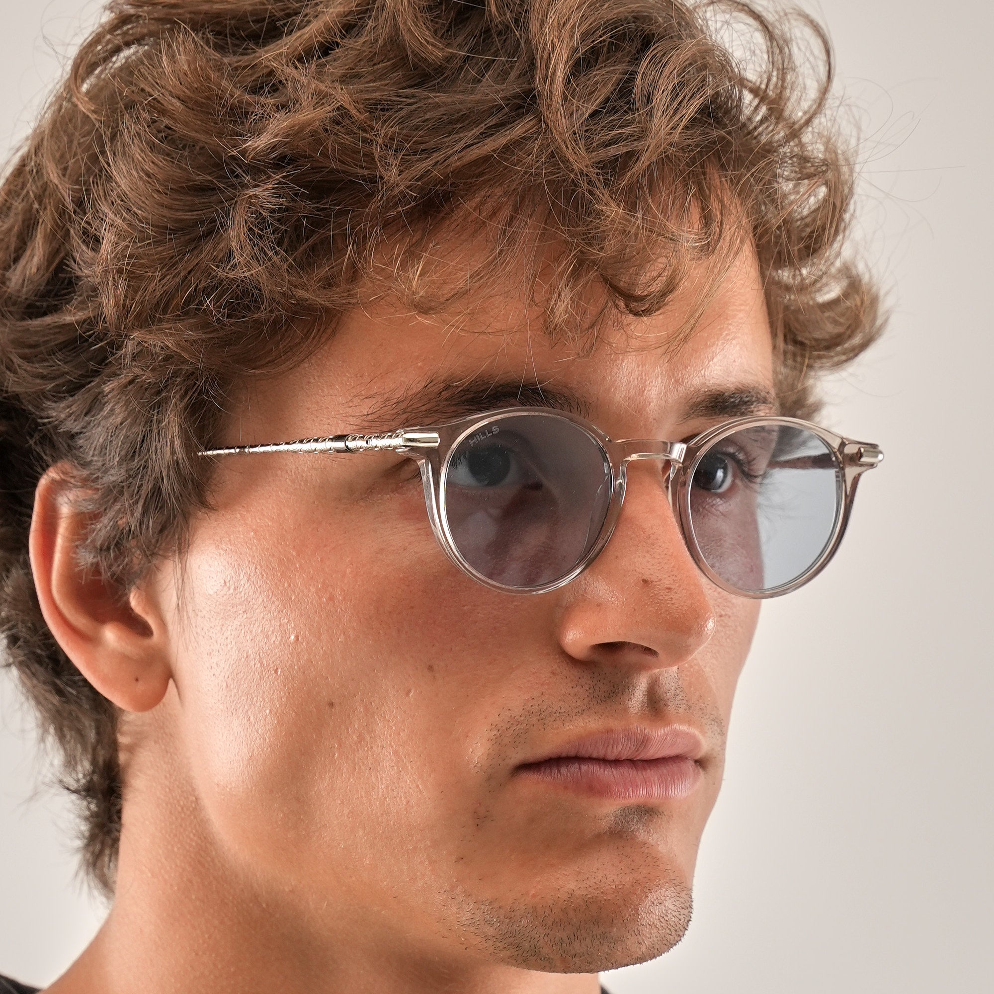 Man wearing round sunglasses with a neutral background